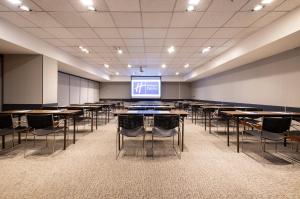 una sala de conferencias con mesas, sillas y una pantalla en Holiday Inn Express Santiago Las Condes, an IHG Hotel, en Santiago