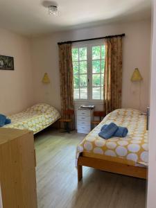a bedroom with two beds and a desk and a window at Le Pre du Moulin in Courniou