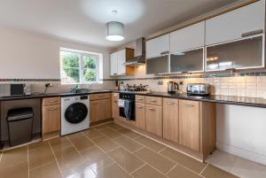 a kitchen with wooden cabinets and a washer and dryer at Holmhill House -Stunning 4-Bedroom Detached House with Ample Driveway for 1-2 Cars in Peterlee