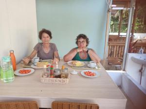 dos mujeres sentadas en una mesa con platos de comida en Renata Cottage, en Langgur