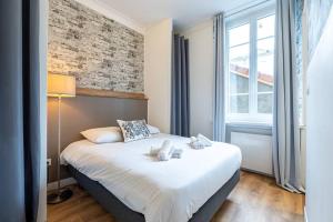 a bedroom with a large white bed with a brick wall at Secteur Gare et GEM: 2 pièces - fibre - confort + in Grenoble
