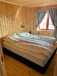 Cama en habitación de madera con ventana en Sollia, en Lifjell