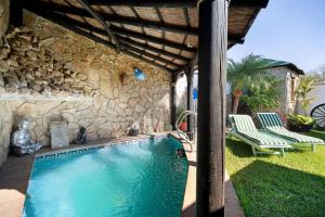 una piscina con 2 sillas y una pared de piedra en Villa Indie, en Chiclana de la Frontera