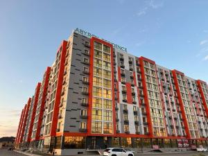 a large red building with a car parked in front at Aportament in Abyroy Residence in Atyrau