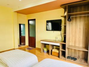 1 dormitorio con 1 cama y TV en la pared en Ngoc Tran Hotel en Da Lat