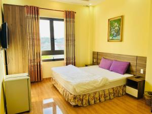 een slaapkamer met een bed met paarse kussens en een raam bij Ngoc Tran Hotel in Da Lat