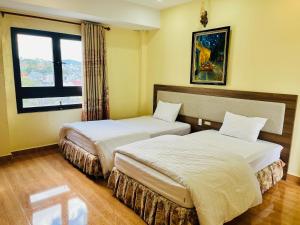 een hotelkamer met 2 bedden en een raam bij Ngoc Tran Hotel in Da Lat