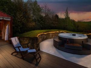 a deck with a hot tub and a chair on a patio at Stable Yard Cottage in Greenlaw