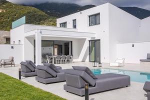 ein weißes Haus mit einem Pool und Liegestühlen in der Unterkunft Eros - Afroditi Villas Collection in Nydri
