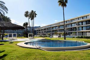 a building with a swimming pool and palm trees at Anacasa Denia Beach AP8209 in Denia