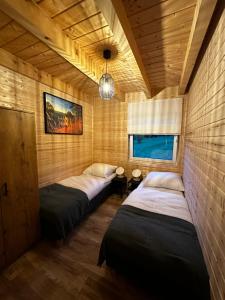 Apartamenty pod Witoszą في Staniszów: غرفة نوم بثلاث اسرة في غرفة بجدران خشبية