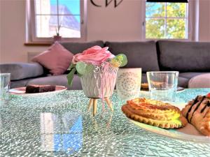 uma mesa de vidro com um vaso de rosas e doces sobre ela em BIG Apartment for YOUR DREAM Vacation Bavarian Forest + NETFLIX em Schöfweg