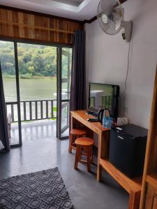 a room with a desk with a television and a balcony at Nam ou view villa in Nongkhiaw