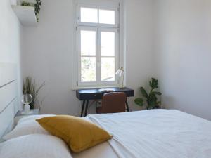 a bedroom with a bed and a desk with a window at Pleasant City Apartment in Graz