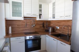 a white kitchen with white cabinets and a sink at Pleasant City Apartment in Graz +2 photos