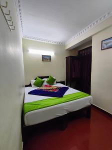 a bedroom with a bed with green and white sheets at Munnar Kaippalli Budget Homestay in Munnar