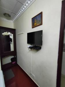 a room with a flat screen tv on a white wall at Munnar Kaippalli Budget Homestay in Munnar