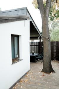a white building with a tree next to it at Tuvāk Saulei in Saulkrasti