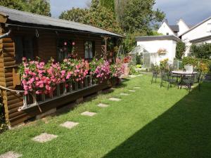 un jardín con flores rosas, mesa y sillas en Ferienwohnung Triska, en Balve