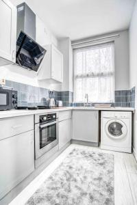a white kitchen with a sink and a dishwasher at Cheerful Flat In Moseley With Free Parking in Birmingham