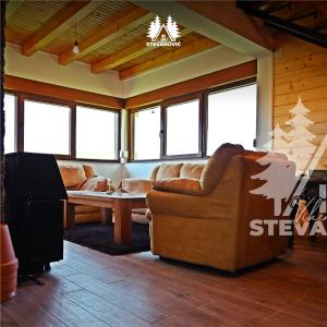 sala de estar con sofás de cuero y TV en Vikendica Stevanovic, en Doboj