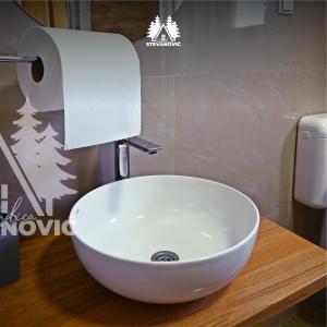 a white sink in a bathroom with a roll of toilet paper at Vikendica Stevanovic in Doboj