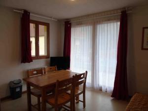 a dining room with a table and chairs and curtains at Appartement Valfréjus, 2 pièces, 4 personnes - FR-1-561-32 in Valfréjus