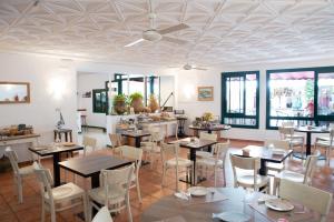 un comedor con mesas, sillas y ventanas en Hostal el Ranxo, en Cadaqués