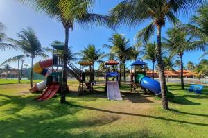 een speeltuin met glijbanen en palmbomen in een park bij Aquaville Resort Pé na Areia 3 suítes 7 Pessoas in Aquiraz
