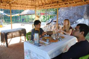 un groupe de personnes assises à une table en train de manger dans l'établissement Khanapara Hilltop Camp, à Guwahati