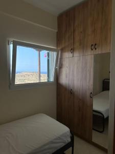 a bedroom with two beds and a window and cabinets at Spiti Filoxenia in Ierápetra