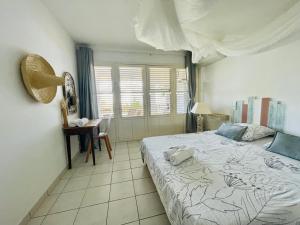 a bedroom with a bed and a table and a window at Sous les Tropiques…Vue mer in Les Trois-Îlets