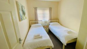 2 łóżka w małym pokoju z oknem w obiekcie Calder Cottage in The Ribble Valley w mieście Whalley