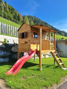 einem Holzspielplatz mit Rutsche und einem Haus in der Unterkunft Ferienwohnung Reicherhof in Sankt Veit im Pongau