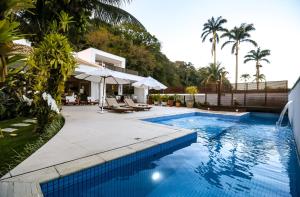 a swimming pool next to a villa with palm trees at Tropical Contemporary Suites in Paraty