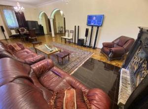 un soggiorno con mobili in pelle marrone e TV di Panorama Dilijan Guest House a Dilijan