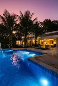 a pool at night with palm trees in the background at Tropical Contemporary Suites in Paraty