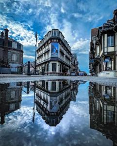 een gebouw met zijn reflectie in een zwembad van water bij Hotel Des Falaises in Étretat