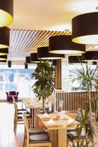 um restaurante com mesas de madeira, cadeiras e plantas em Hotel No151 em Differdange