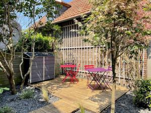 2 sillas rojas y una mesa en una terraza de madera en Le Villervillais CLS Deauville en Villerville