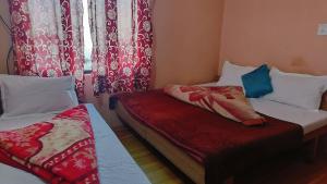 Cette petite chambre comprend 2 lits et une fenêtre. dans l'établissement Neeraj Homestay, à Dharamshala