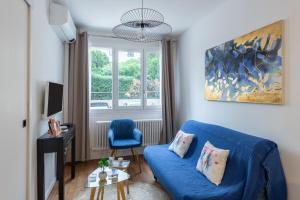 a living room with a blue couch and a window at Cosy Vendôme - A 5min du Parc de la Tête dOr in Lyon