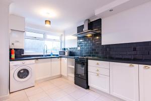 a kitchen with white cabinets and a washer and dryer at Bodmin House - Charming 3-Bedroom Terrace House with Private Enclosed Garden in Wallsend