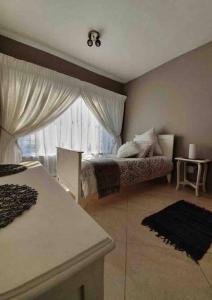 um quarto com uma cama e uma grande janela em 36 Petrel Road em Centurion