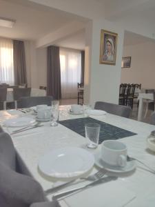 una mesa con platos blancos y vasos. en Pansion Vesna&Vlado Ostojic, en Međugorje