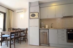 uma cozinha com uma mesa e um frigorífico branco em Jardins del Mar 48 em L'Estartit