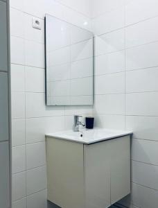 een witte badkamer met een wastafel en een spiegel bij The artist's apartment near the metro in Saint-Denis