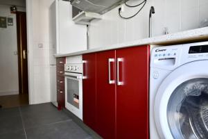 cocina con lavadora y armarios rojos en For You Rentals Coqueto y Cómodo apartamento Madrid, en Madrid