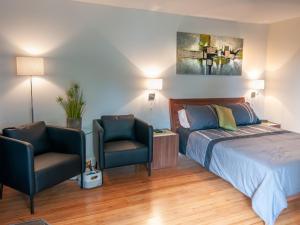 sypialnia z łóżkiem i 2 krzesłami w obiekcie Résidence Touristique Chicoutimi w mieście Saguenay