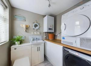 een kleine keuken met een wastafel en een wasmachine bij The Terrace Hoole, cosy modern 2 bedroom house in Chester